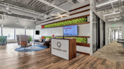 Main lobby area with open Coworking seating, front desk, views of the city, and main hallway with built-in water fountain.