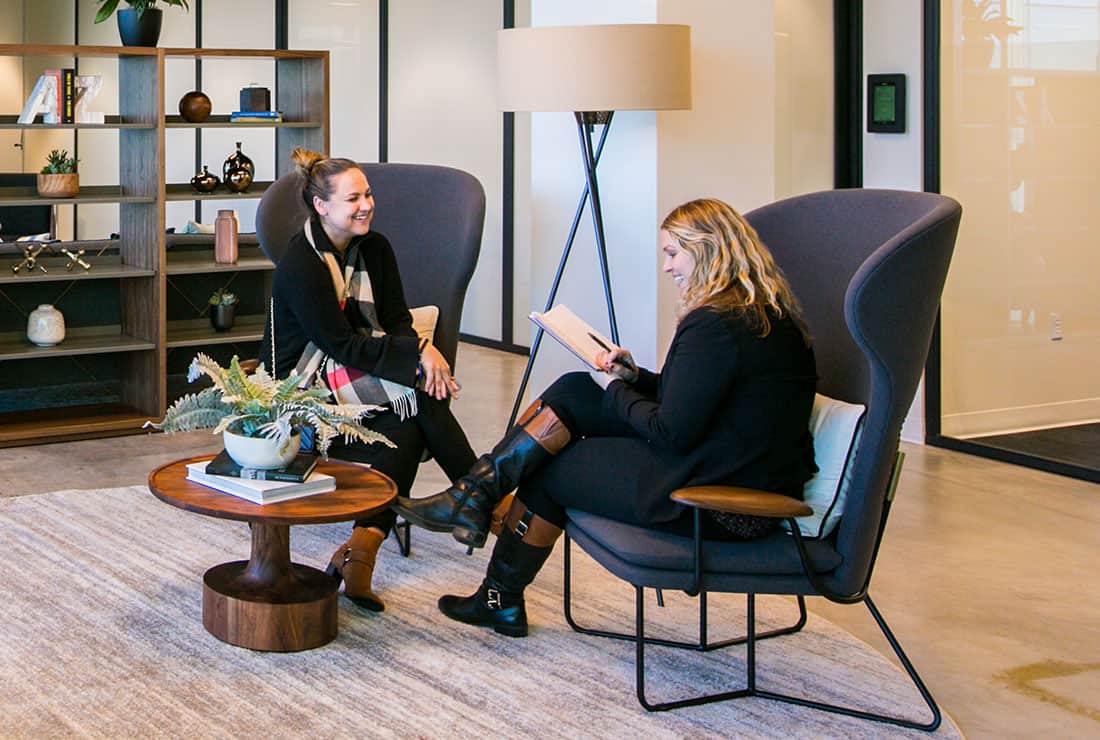 Two women conversing on comfy chairs in our open Coworking space.