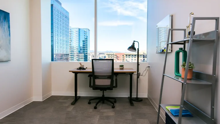 Private spacious one person office with a desk, bookcase, and view of the skyline, LoDo Denver Private Office & Coworking Space