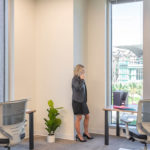 Woman on phone in a Private 2 person office, looking at the downtown through her window.