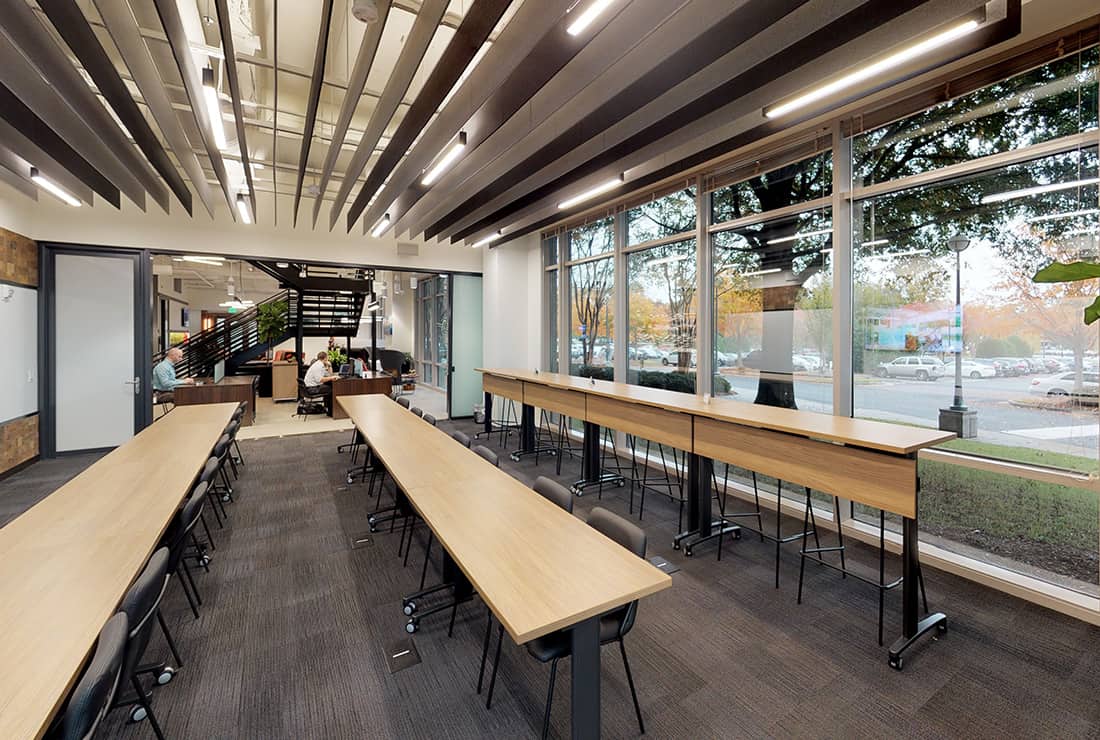 Open Ideation studio with high and low seating and built in A/V system for meetings, next to the Coworking area where members are working independently.