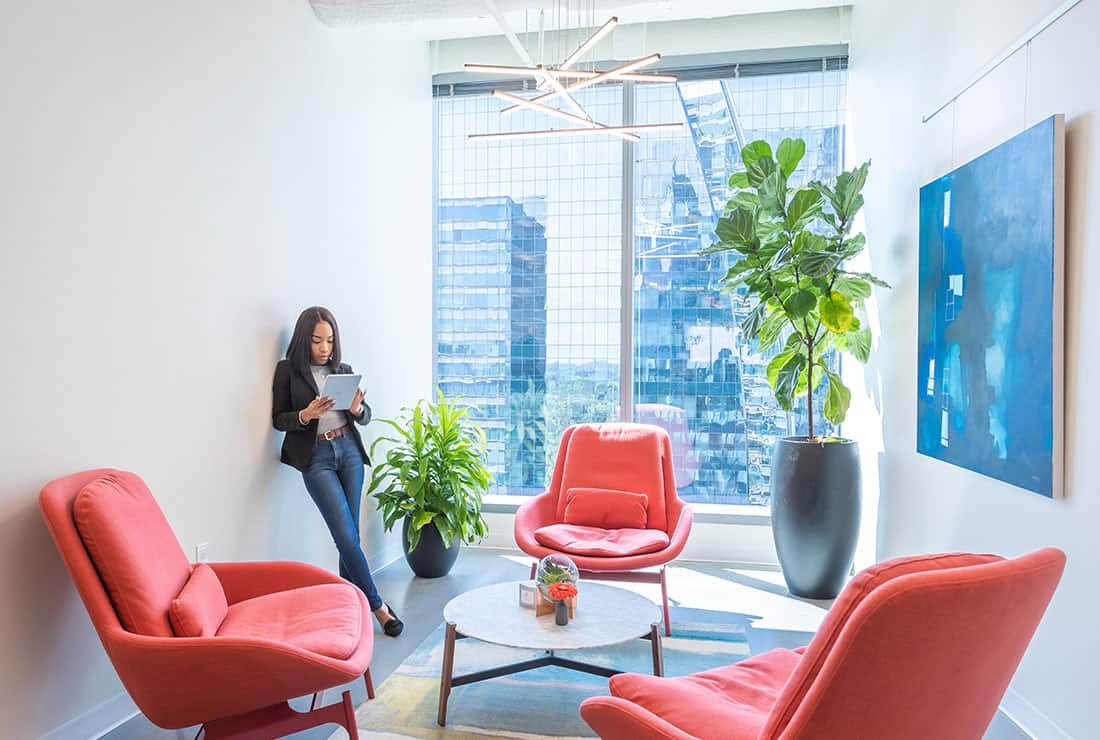 Woman standing while working in open Coworking space with window views of Downtown.