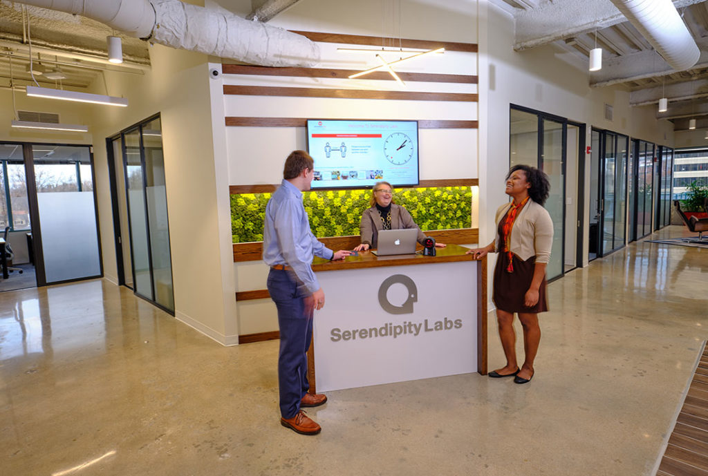 Two members conversing with the Experience Coordinator at the front desk.