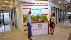 Two members conversing with the Experience Coordinator at the front desk.