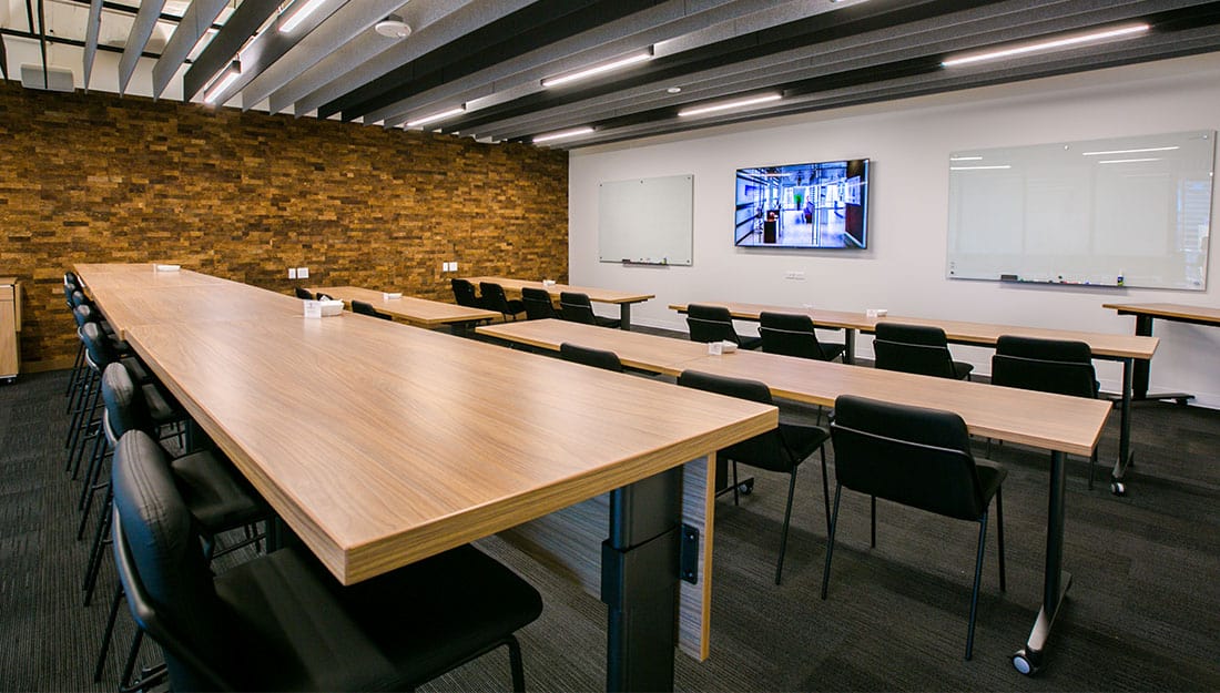 Large Ideation Studio with wooden accents, lots of seating, and a built in A/V system.