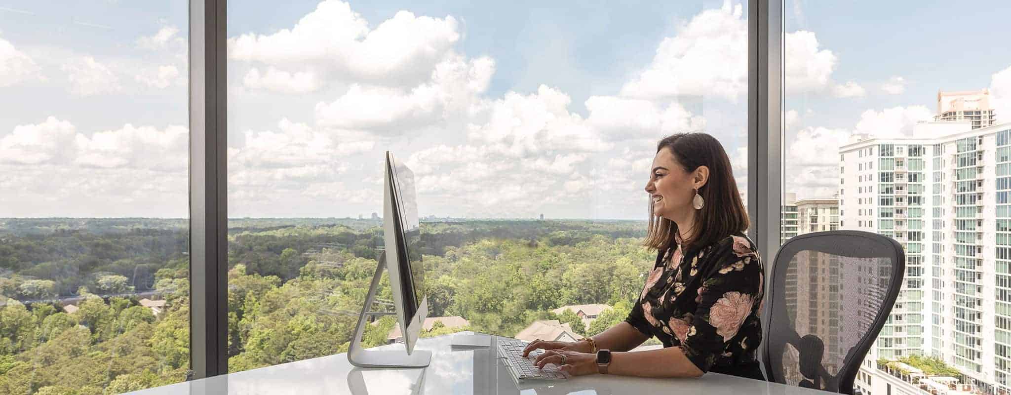 Woman working independently in her private office with outdoor views.