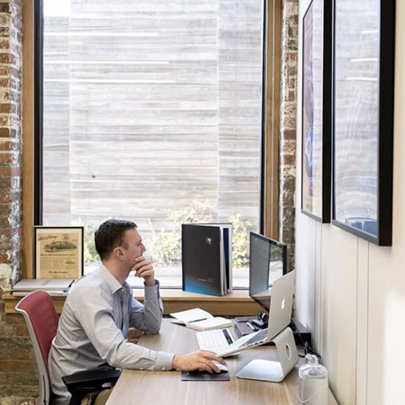 Man working at a Dedicated Desk in Coworking area by the window.