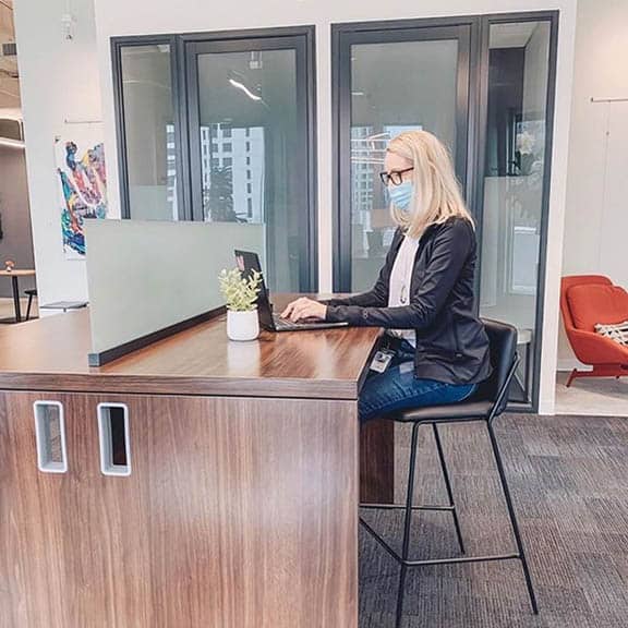 Woman working at Coworking desk with her mask on.