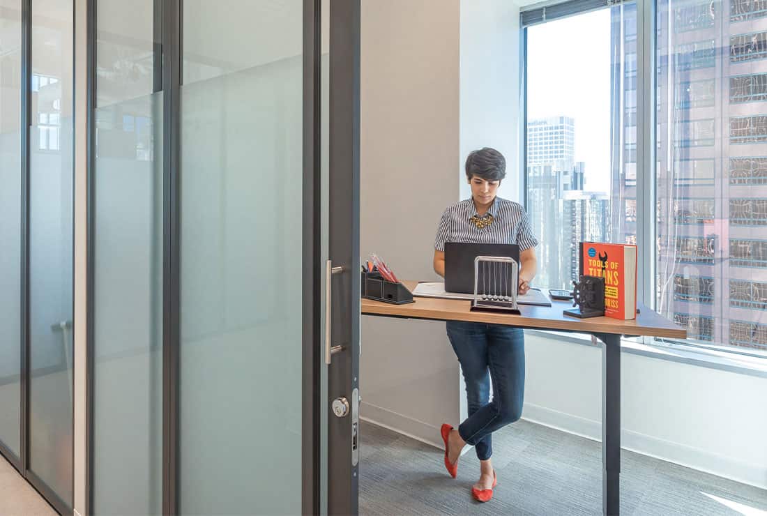 Woman working in a one person private office, with a view of the city.