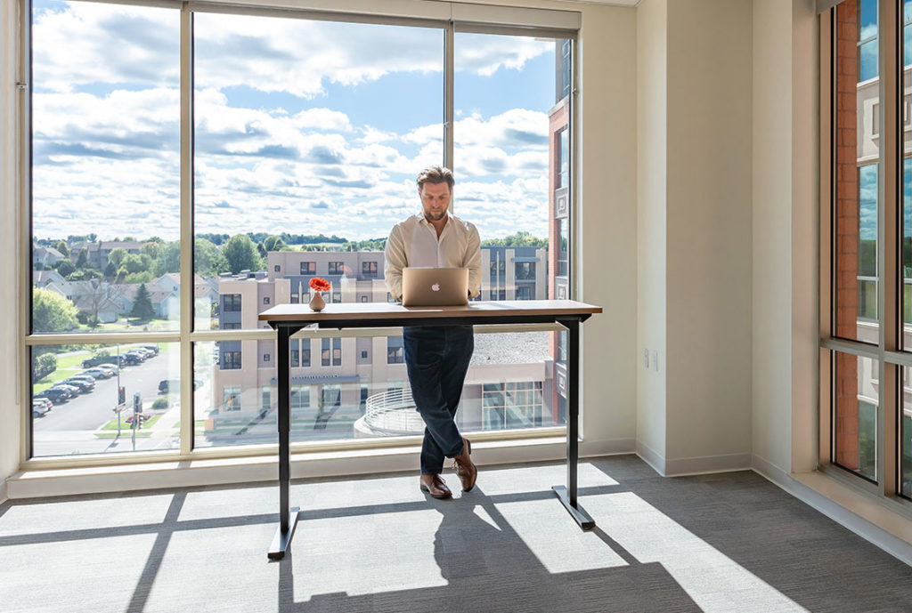 A man working in a private office with a large window view behind him.