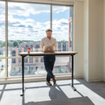 A man working in a private office with a large window view behind him.