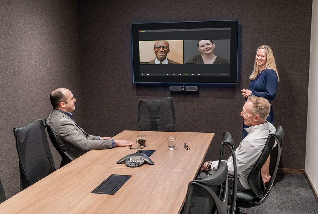 Three members having a meeting in the Visual studio utilizing the built-in A/V system for a conference call.