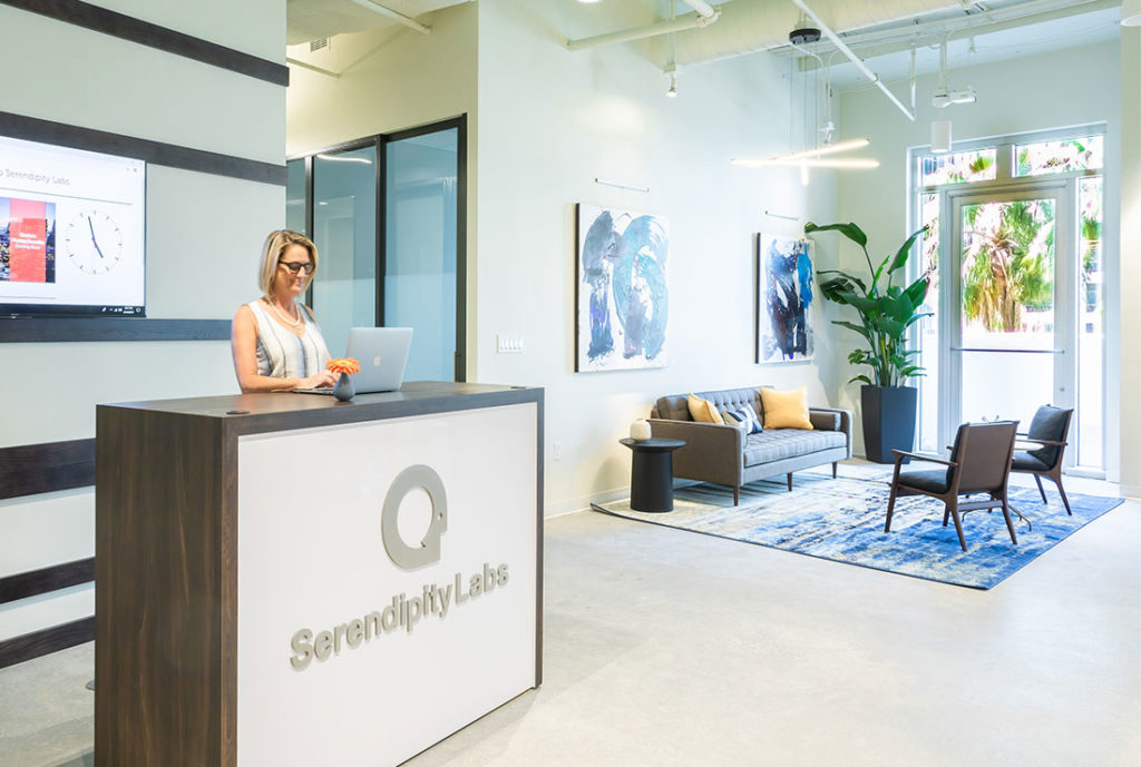 Experience Coordinator working at front desk next to private offices and Coworkingseating.